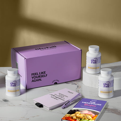 A product bundle display for GleeFull Supplements on a marble surface against a yellow background. The layout includes a large purple shipping box featuring the slogan 'FEEL LIKE YOURSELF AGAIN.', three white bottles of Cool REM Sleep, a purple branded pen, a matching notepad that reads 'REMINDERS WHEN I'M HAVING A MENOPAUSE MOMENT', and a recipe booklet titled 'THE MENOPAUSE Recipes'