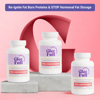 Product display for GleeFull Meno-Shred Fat Burner dietary supplement. A purple banner across the top reads: 'Re-ignite Fat Burn Proteins & STOP Hormonal Fat Storage'. Three white bottles with purple and cream labels are arranged on grey marble blocks against a pink background with a large coral letter G graphic. Each label reads 'GleeFull Supplements, Support Metabolism & Energy, Meno-Shred Fat Burner, Dietary Supplement, 60 Capsules'.
