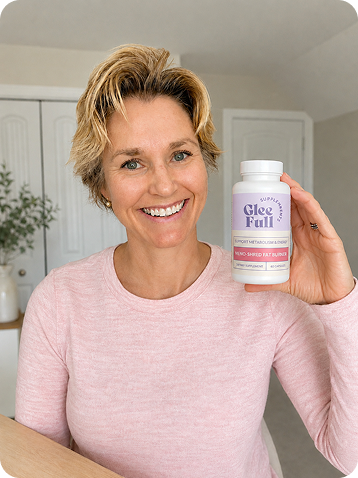 Smiling woman in a pink top holding a bottle of Gleefull Meno-Shred